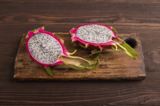 Ripe Pitaya on cutting board on brown wooden background, side view, copy space, minimalism
