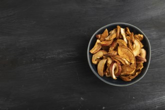 Dried Apples in ceramic bowl on black wooden background. Top view, copy space, flat lay. healthy