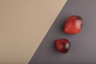 Red Heart shape tomatoes on gray and beige pastel paper background. Top view, copy space, flat lay.