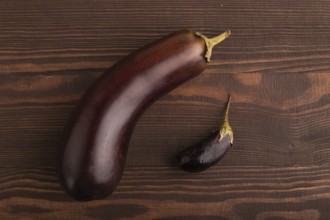 Two Eggplants big and small on brown wooden background, top view, flat lay, copy space, minimalism