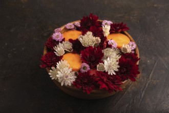 Wooden bowl with carrot slices and red Chrysanthemum flowers, Astrantia flowers, flower salad on