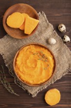 Sweet potato porridge in wooden bowl on wooden background and linen textile. Diet, healthy eating