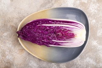 Purple Chinese cabbage on blue plate on brown concrete background, top view, flat lay, close up,