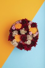 Wooden bowl with carrot slices and red Chrysanthemum flowers, Astrantia flowers, flower salad on