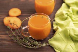 Two glasses with carrot juice, on wooden background and green textile. Diet, healthy eating concept