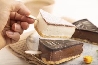 Chocolate and Vanilla Cake pops Marshmallow with hand with cup of coffee on white wooden background