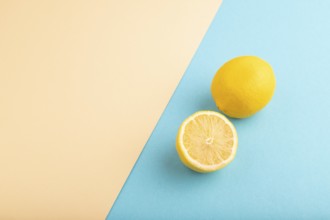 Yellow Lemon Cut in half on orange and blue pastel paper background. Side view, flat lay, copy