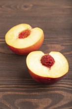Peach Cut in half on brown wooden background. Side view, flat lay, close up. healthy food,
