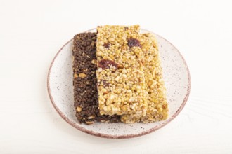 Granola bars with caramel, nuts, flakes in ceramic plate on white wooden background. Side view,
