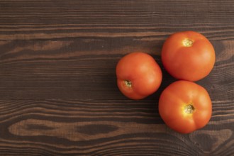 Red tomato on brown wooden background. Top view, flat lay, copy space. healthy food, vegetable,