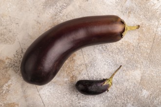 Two Eggplants big and small on brown concrete background, top view, flat lay, close up, minimalism