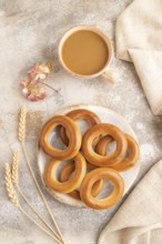 Homemade Ring Bagel with cup of coffee on brown concrete background and linen textile. top view,