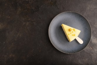 Yellow Cake pop with sprinkles on blue ceramic plate on black concrete background, top view, flat