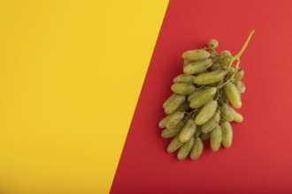 Green grapes on yellow and red paper pastel background. Top view, flat lay, copy space. healthy