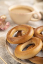 Homemade Ring Bagel with cup of coffee on brown concrete background and linen textile. side view,