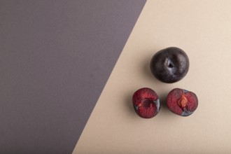 Purple Plum Cut in half on beige and gray pastel paper background. Top view, flat lay, copy space.