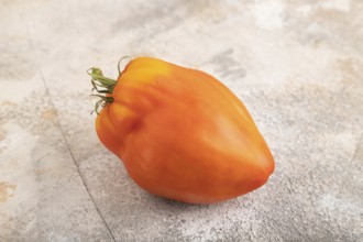 Red Heart Shape tomato on brown concrete background. Side view, close up. healthy food, vegetable,