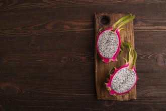 Ripe Pitaya on cutting board on brown wooden background, top view, flat lay, copy space, minimalism