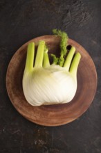 Fresh Fennel bulb on wooden cutting board on black concrete background, top view, flat lay, copy