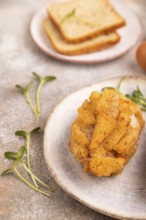 Chicken Schnitzel on blue plate with microgreen on brown concrete background and orange linen
