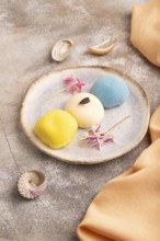 Japanese Mochi Cakes on brown concrete background and orange textile, side view, close up