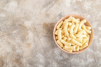 Corn flakes sticks with caramel in ceramic bowl on gray concrete background. Top view, flat lay,