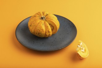 Orange Pumpkin cutted on blue plate on orange pastel paper background. Side view, copy space,