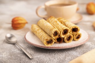 Waffles with caramel on brown concrete background and orange linen textile, cup of coffee, side