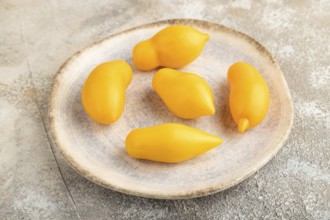 Yellow tomatoes on plate on brown concrete background. Side view, close up. healthy food,