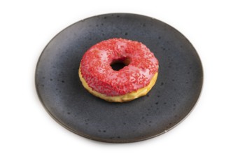 Pink Donut with sprinkles on blue ceramic plate isolated on white background, side view, close up,