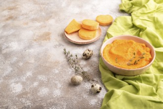Sweet potato porridge in ceramic bowl on brown concrete background and green textile. Diet, healthy