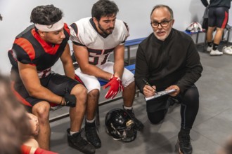American football coach on a knee formulating game strategy and providing guidance on a clipboard