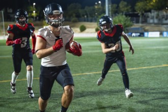 American football players, wearing protective helmets and pads, are running on a green turf field