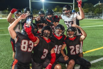 American football teammates in uniform celebrate a win on the field, smiling and posing for a group