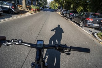 Cycling in the city, city centre street, shadow of the biker, cyclist perspective, Essen, North
