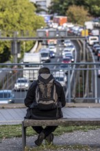 Man sitting on a bench, looking at the traffic jam on the A40 motorway, Ruhrschnellweg, in the city