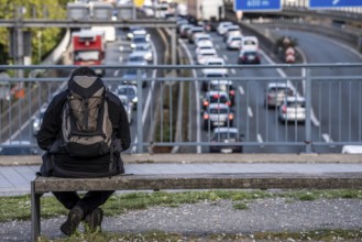 Man sitting on a bench, looking at the traffic jam on the A40 motorway, Ruhrschnellweg, in the city
