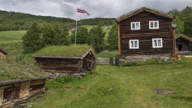 Norwegische Holzhäuser mit Gras auf den Dächern, Fahnenmast mit Norwegen-Flagge, historischer