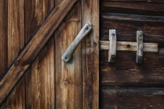 Nahaufnahme eines rustikalen Holztürbeschlags mit einem einfachen Riegel, historischer Bauernhof