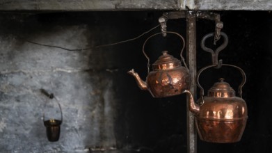 Alte Kupferkessel, die an Haken in einer rustikalen Küche hängen, historischer Bauernhof und