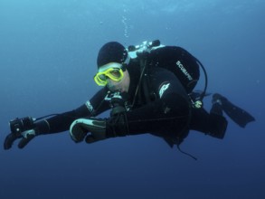 Ein Taucher in voller Ausrüstung kontrolliert unter Wasser seinen Tauchcomputer. Tauchplatz Wrack