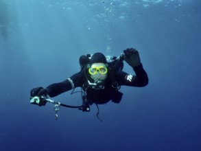 Ein Taucher mit kompletter Tauchausrüstung streckt seinem Tauchpartner, dem offenbar die Luft