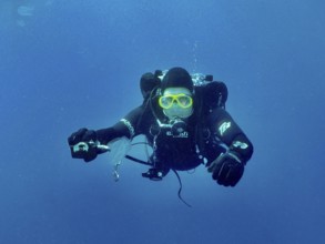 Ein Taucher mit kompletter Tauchausrüstung streckt seinem Tauchpartner, dem offenbar die Luft