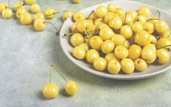 Yellow cherry, cherry berry, scattered on a plate, top view, no people