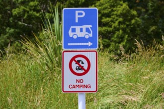 Ein Schild weist auf Parkmöglichkeiten für Wohnmobile hin und verbietet Camping, umgeben von Gras