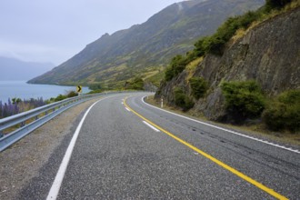 Kurvige Küstenstraße entlang von Felsen mit Blick auf den See, Lake Wanaka, The Neck, Otago,