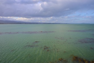 Grünes Wasser Meer breitet sich unter einem bewölkten Himmel aus, Moeraki, Hampden, North Otago,