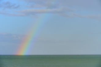 Ein Regenbogen über dem blauen Meer unter einem wolkigen Himmel, Moeraki, Hampden, North Otago,