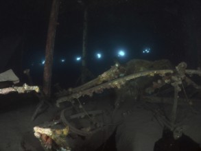 Weathered remains of a wreck under water, overgrown with algae, mysterious darkness. Dive site