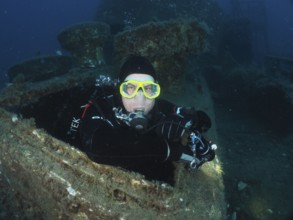 Diver looking out of the hatch of a wreck. Dive site wreck of the Vis, Pula, Croatia, Mediterranean